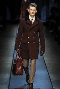 Мужское драповое пальто на зиму двубортного фасона цвета жженой умбры от Canali в сочетании с брюками светло-коричневого оттенка, сумкой коричневого тона Canali и туфлями тёмно-коричневой расцветки от Canali.