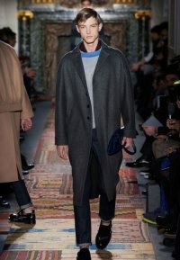 Драповое пальто однобортного фасона тёмно-серого оттенка длиной ниже колен от Valentino в сочетании с джинсами тёмно-синего тона, свитером серого цвета Valentino и чёрными туфлями Valentino.