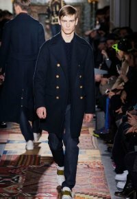 Зимнее драповое пальто полуночно-синего оттенка двубортного фасона из новой коллекции Valentino в сочетании с вязаным свитером тёмно-синего тона, синими джинсами Valentino и туфлями бело-коричневой расцветки от Valentino.