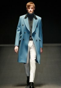 Кожаное пальто для мужчин двубортного фасона небесно-голубого тона с длиной до колен из новой коллекции Gucci в сочетании с пуловером серого цвета, белыми брюками Gucci и туфлями чёрного цвета от Gucci.