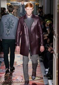 Кожаное зимнее пальто сливового оттенка двубортного фасона длиной выше колен из новой коллекции Valentino в сочетании с вязаным свитером серого тона, брюками асфальтного цвета Valentino и кроссовками серо-коричневой расцветки Valentino.