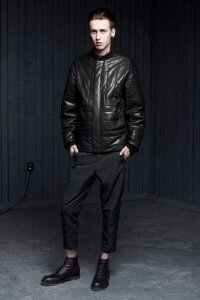 Мужское стеганое пуховое пальто чёрного цвета из коллекции Alexander Wang в сочетании с брюками чёрного тона Alexander Wang и чёрными ботинками чёрной расцветки от Alexander Wang.