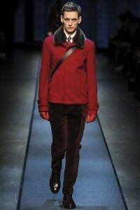 Короткое зимнее пальто для мужчин красного цвета с меховым воротником из новой коллекции Canali в сочетании с брюками бордового тона Canali и туфлями шоколадного оттенка от Canali.