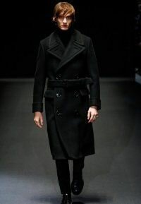 Длинное чёрное мужское пальто на зимний период двубортного фасона с широким поясом от Gucci в сочетании с классическими чёрными брюками Gucci и туфлями чёрной расцветки Gucci.